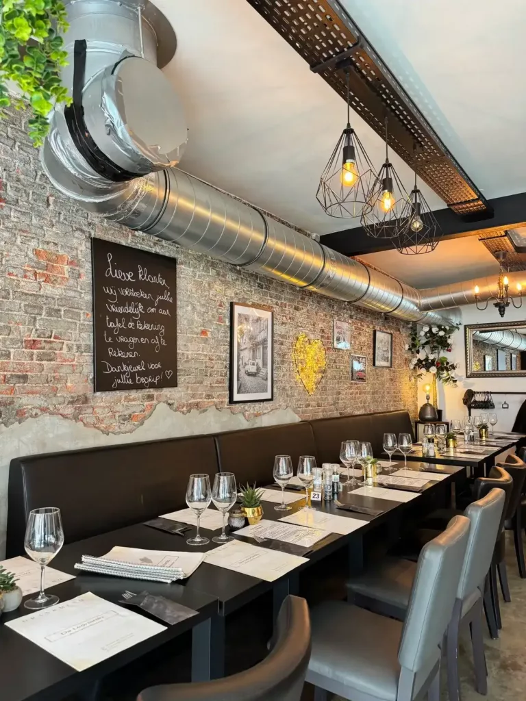 Eetzaal van Da Leonardo met krijtbord, hanglampen en gedekte tafels