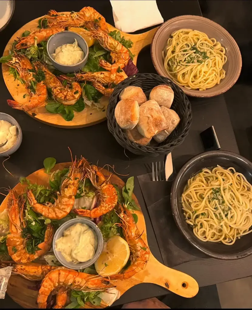 Tafel met gegrilde gamba's, spaghetti en brood om te delen